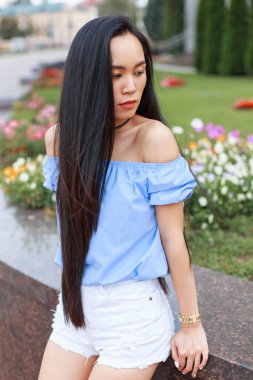Uzun saçlı, mavi bluzlu ve şortlu güzel bir Asyalı kadın mankeni.