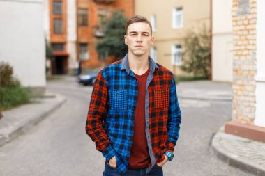 Moda tarzı olan, renkli tişörtlü şık bir genç adam sokakta yürüyor.