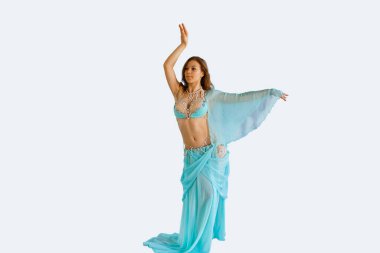Seksi mavi kostümlü güzel kız oryantal göbek dansı yapıyor izole beyaz arka planda dans ediyor.