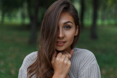 Parkta örülmüş süveteri olan güzel ve güzel bir manken.