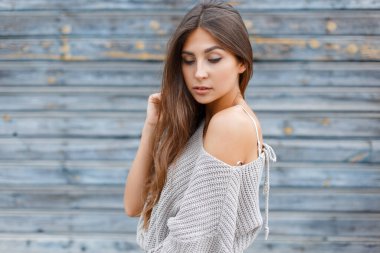 Moda kıyafetleri içinde genç ve güzel bir kız model. Eski mavi ahşap arka planda süveter örüyordu.