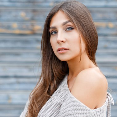 Mavi, eski, ahşap arka planda kazak giyen doğal, taze, güzel bir kadın. KADIN PORTESİ