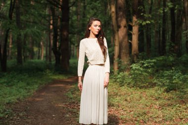 Moda örgü süveter içinde, ormanda yeşil doğal bir arka planda güzel, taze, genç bir kadın.