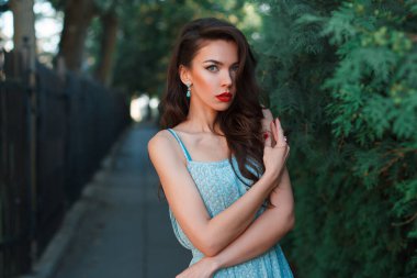 Parkta, kırmızı dudaklı, modaya uygun elbisesi olan zarif, genç bir kız.