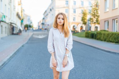 Moda elbisesi ve gömleğiyle şehirde gezen zarif genç bir manken.