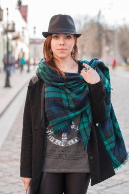 Eski moda şapkalı ve siyah ceketli genç moda güzeli şehirde yürüyor.