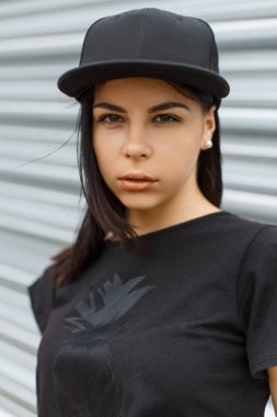 Moda modası geçmiş, siyah tişörtlü, sokakta metal arka planda modaya uygun bir hippi kadın.