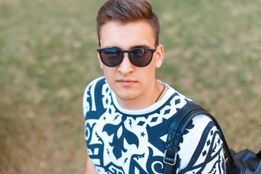 Havalı, yakışıklı, stil sahibi, vahşi, güneş gözlüklü, doğa yürüyüşlü bir adam.