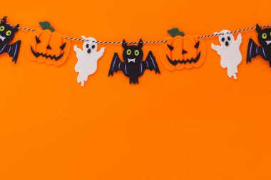 Balkabağı, yarasa ve hayaletli süslemeler turuncu arka planda yatar. Mutlu Cadılar Bayramı kartı, tasarım ve metin için boş alan