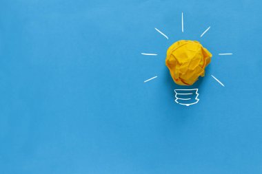 İlham konsepti buruşmuş kağıt ampul metaforu iyi fikir için. Sarı buruşmuş kağıt ampul mavi arka plana çizilmiş. Beyin fırtınası ve yaratıcı fikir, konsept. Proje ve başlangıç