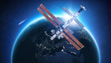 UUİ, güneş batarken Mavi Gece Gezegeni Dünya 'nın yakınında uçuyor. Uzay görevi ve uzay keşfi. Dünya yörüngesindeki iletişim ve teknolojiler