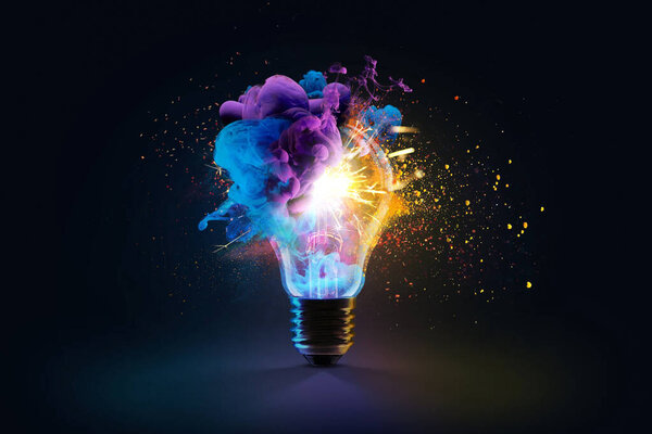 Creative light bulb explodes with colorful dry paint, sparks and splashes on a black background, concept. Think differently creative idea concept. Motion Color drop in water, Ink swirling