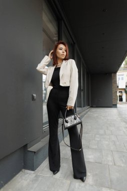 Bir kadının tam boy portresi. Şık iş kıyafetleri içinde şehir ortamında kendine güvenen bir kadın girişimci. Başarı ve güçlendirme kavramı.