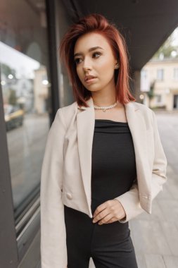 Şık, alımlı, alımlı, genç bir iş kadını. Moda modasına uygun giyinmiş, spor ceketli, şehirde yürüyen bir kadın. Şehir kızı.