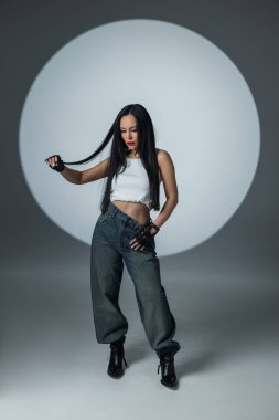 Gevşek kotlu genç bir manken ve stüdyo ışıkları altında kendine güvenen bir bluz..