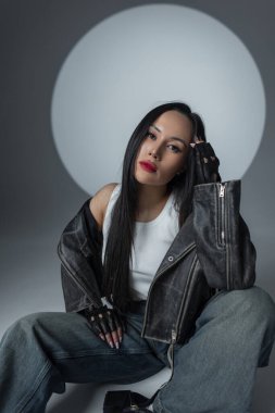 Şık şehir modasını cesur makyaj ve dramatik pozlarla sergileyen şık bir model. Deri, kot ve sahne ışıkları altında kendine güven.