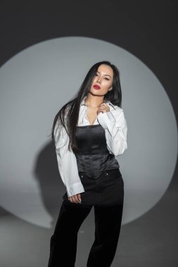 Siyah uzun saçlı, kırmızı dudaklı, siyah beyaz ve siyah arka planda poz veren bir manken. Yüksek karşıtlık ve yazı tipi.