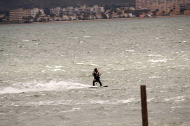 Sahilde siyah takım elbiseli bir adam.