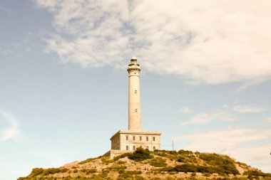 Güzel havanın pelerininin tepesinde bir deniz feneri