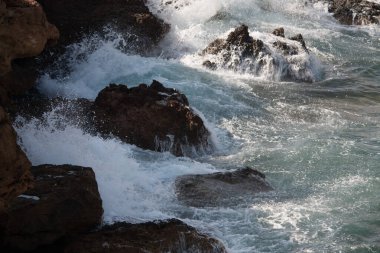 Dalgalar kayalık bir sahile çarpıyor.