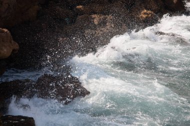 Kayalar üzerinde deniz dalgaları, deniz köpüğü ve su sıçramaları..