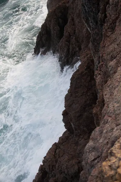 Dalgalar okyanusun kıyısındaki kayalara çarpıyor.