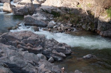 Ormandaki kayalık dağların arasından akan nehirli güzel bir kaya görüntüsü.