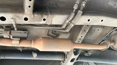 Katalitik dönüştürücü. Modern araba alt görüşünün egzoz borusu sistemi. Paslı ve kirli araba parçaları, kaldırılmış araba parçaları.