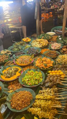 Çeşitli sebzeler ve geleneksel Endonezya yemekleri de dahil olmak üzere yiyecek dolu bir masa.