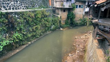 Asya 'nın yoğun nüfuslu şehrinde kirlenmiş küçük bir nehir, çöp, plastik ve çöplerle dolu kirli su, gecekondu bölgesi