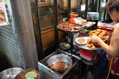 Bangkok, Thailand - November 16, 2024: old grandma fried food, famous local cuisine at Chatuchak Weekend Market, crowded with people and tourists who come out to eat clipart