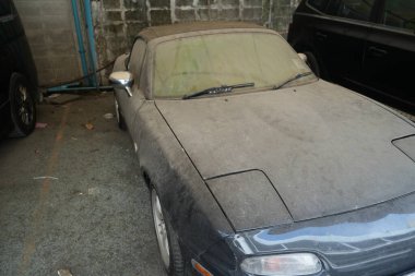 Bangkok, Tayland - 27 Kasım 2024: Terk edilmiş mazda miata mx5, toz ve kir kaplı, aniden parlayan far ve üstü açık araba