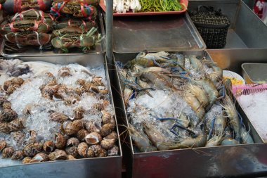 Taze deniz ürünleri tezgahında taze deniz ürünleri sergileniyor. Karides, klemp ve yengeç var.