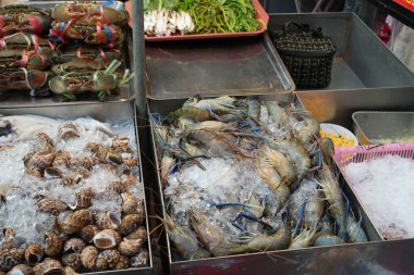 Taze clanp ve taze dev tatlı su nehir karidesi. Taylandlılar için buz gibi soğuk. Yabancı gezginler Bangkok 'taki yemek restoranında aşçılık mutfağını ziyaret ediyor ve seçiyor.