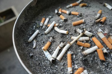 Kül tablasında sigara izmaritleri, içtikten sonra bir sürü sigara kalıntısı.