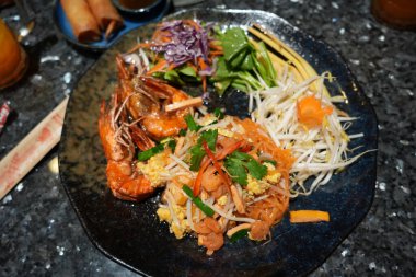 Tayland usulü limon ve baharatla servis edilen Pad Thai veya Tayland usulü Tayland yemeği, Tayland 'da sokak yemeklerinde bulunabilen bir yemektir..