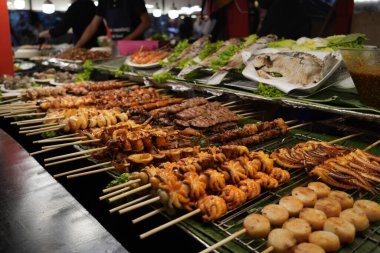 Barbekü dükkanında çeşitli deniz ürünleri şişlenmiş malzemeler sergiliyor. Gece Pazarı, ekonomik ve çeşitli yiyecekler.