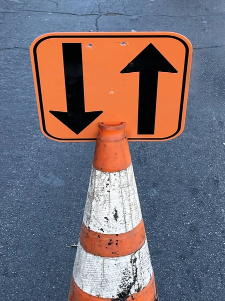Sign on a traffic cone at a street construction site announcing two way traffic