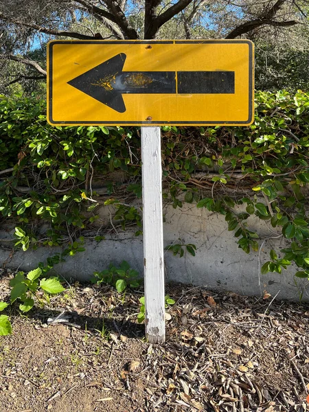 Black arrow to the left on a yellow road sign at the end of a street