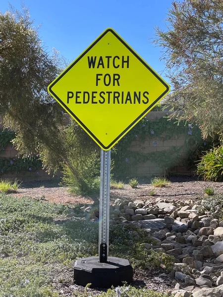 WATCH FOR PEDESTRIANS sign in a park landscape