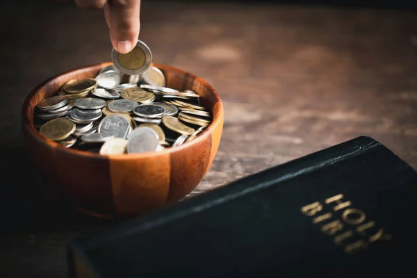 One tenth or tithe is basis on which Bible teaches us to give one tenth of first fruit to God. coins with Holy Bible. Biblical concept of Christian offering, generosity, and giving tithes in church.