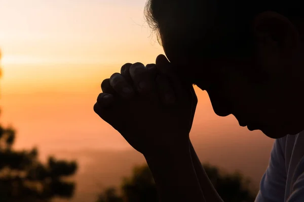 Faith of christian concept: Spiritual prayer hands over sunshine with blurred beautiful sunrise or sunset background. Christians who have believe, faith in God morning prayer.