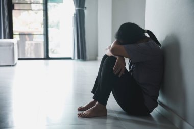 Schizophrenia with lonely and sad in mental health depression concept. Depressed woman sitting against wall at home with a shadow on wall feeling miserable. Women are depressed, fearful and unhappy. clipart