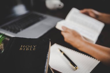 Evde ders çalışarak İncil 'i tutan genç bir kadın. Kilisede yetişkin bir Hıristiyan kadın kitap okuyor. Din maneviyatını Tanrı 'ya dua ederek öğrenen bir kız. Öğrenci eğitimi inancı kavramı.