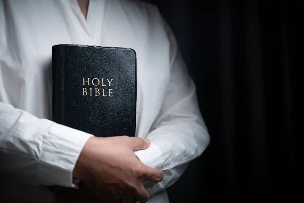 stock image Faith with holy bible concept. Hands of a female prayer worship God with holy bible on black background in church. Christian woman who believe in Jesus read and study the grace of the holy scriptures.