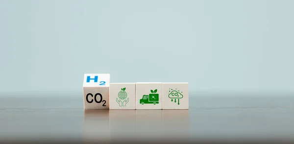 Free Carbon, alternative energy and global climate change concepts. Hand flipping wooden cube blocks with CO2 Carbon dioxide, change to H2 Hydrogen text on table background. Sustainable car energy.