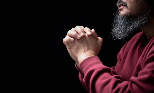 Hands folded in prayer on in church concept for faith, spirituality and religion, man praying in the morning. man hand with praying god. Person Christian men who have faith in Jesus worship in dark.