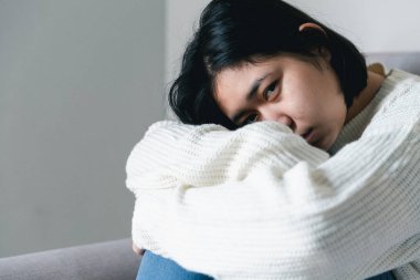 Concept of sad teenage girl depression. Upset teenage girl sitting at window indoors. Anxiety young woman Despair and stress. Lonely and unhappy female are social victims. loneliness youth in home.