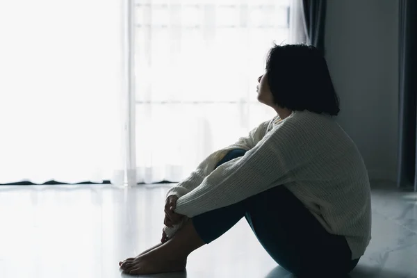 Concept of sad teenage girl depression. Upset teenage girl sitting at floor indoors. Anxiety young woman Despair and stress. Lonely and unhappy female are social victims. loneliness youth in home.