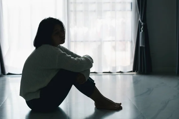 Concept of sad teenage girl depression. Upset teenage girl sitting at floor indoors. Anxiety young woman Despair and stress. Lonely and unhappy female are social victims. loneliness youth in home.